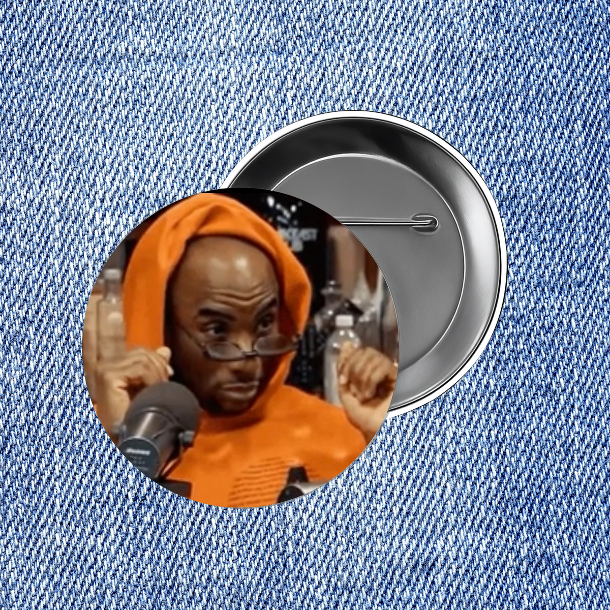 a close-up of a person wearing an orange hoodie and glasses, with a silver pin visible in the background.
