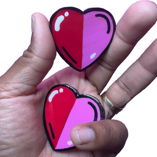 a person holding two heart shaped magnets in their hand